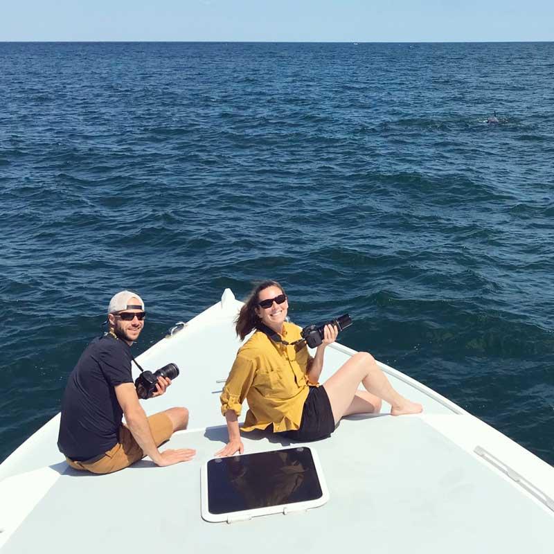 Photo: Ph.D. students Jillian Wisse and Joe Fader conducting fieldwork this summer. Cameras are a field essential, as individual whales can be identified by unique markings on their bodies and dorsal fins.