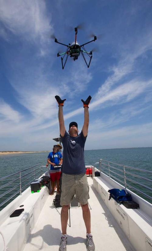 Everette Newton holding his arms up, pointing towards a drone.