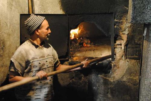 A photo of a man putting something in an oven.